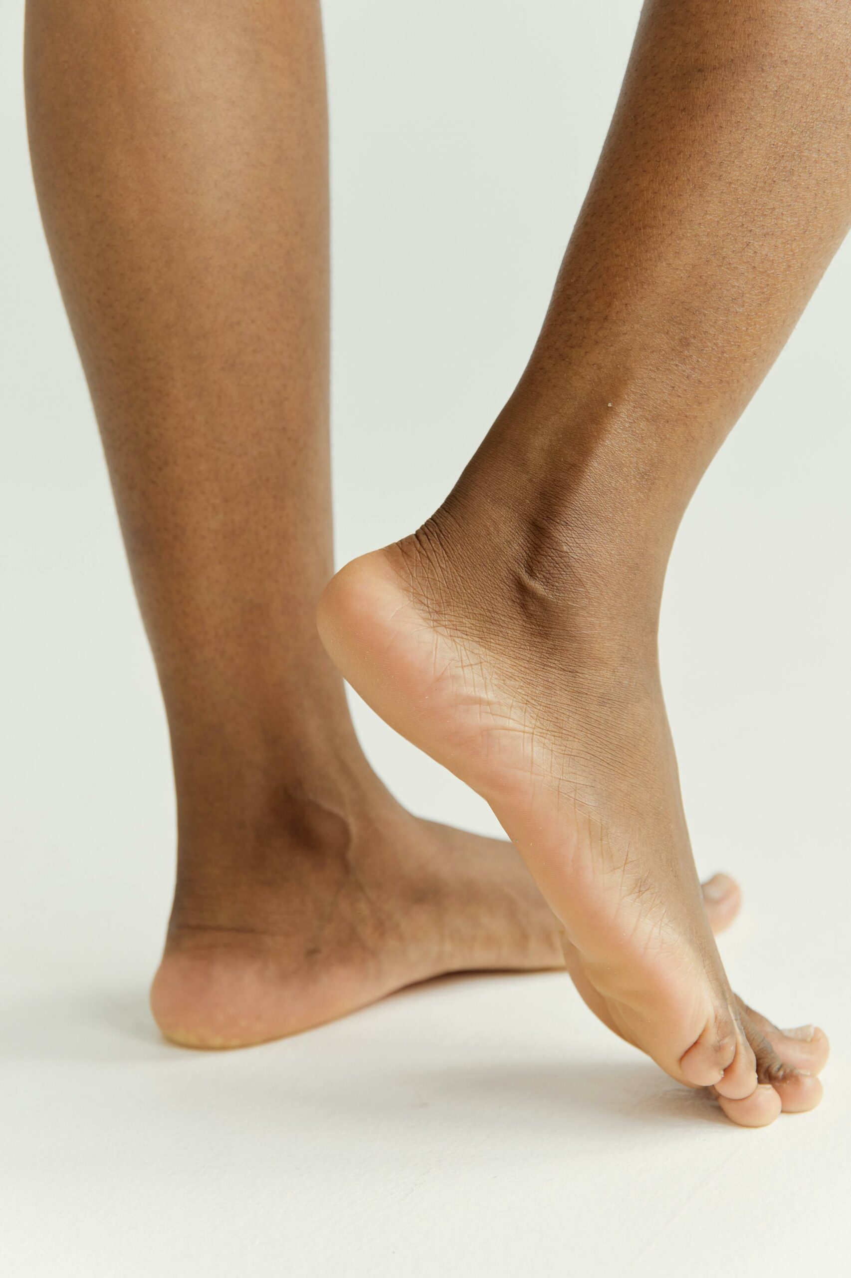 Detailed close-up of feet on a neutral background focusing on skin tone and texture.